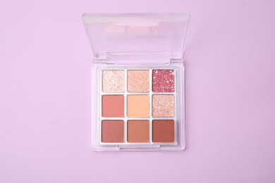 Photo of Beautiful eye shadow palette on lilac background, top view
