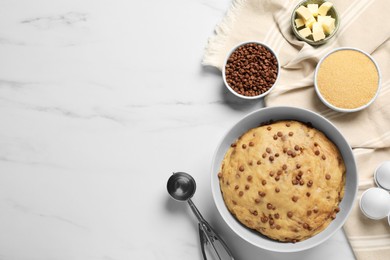 Photo of Bowl with dough and ingredients for cooking chocolate chip cookies on white marble table, flat lay. Space for text