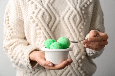 Photo of Woman eating snow ice cream from bowl on light background, closeup