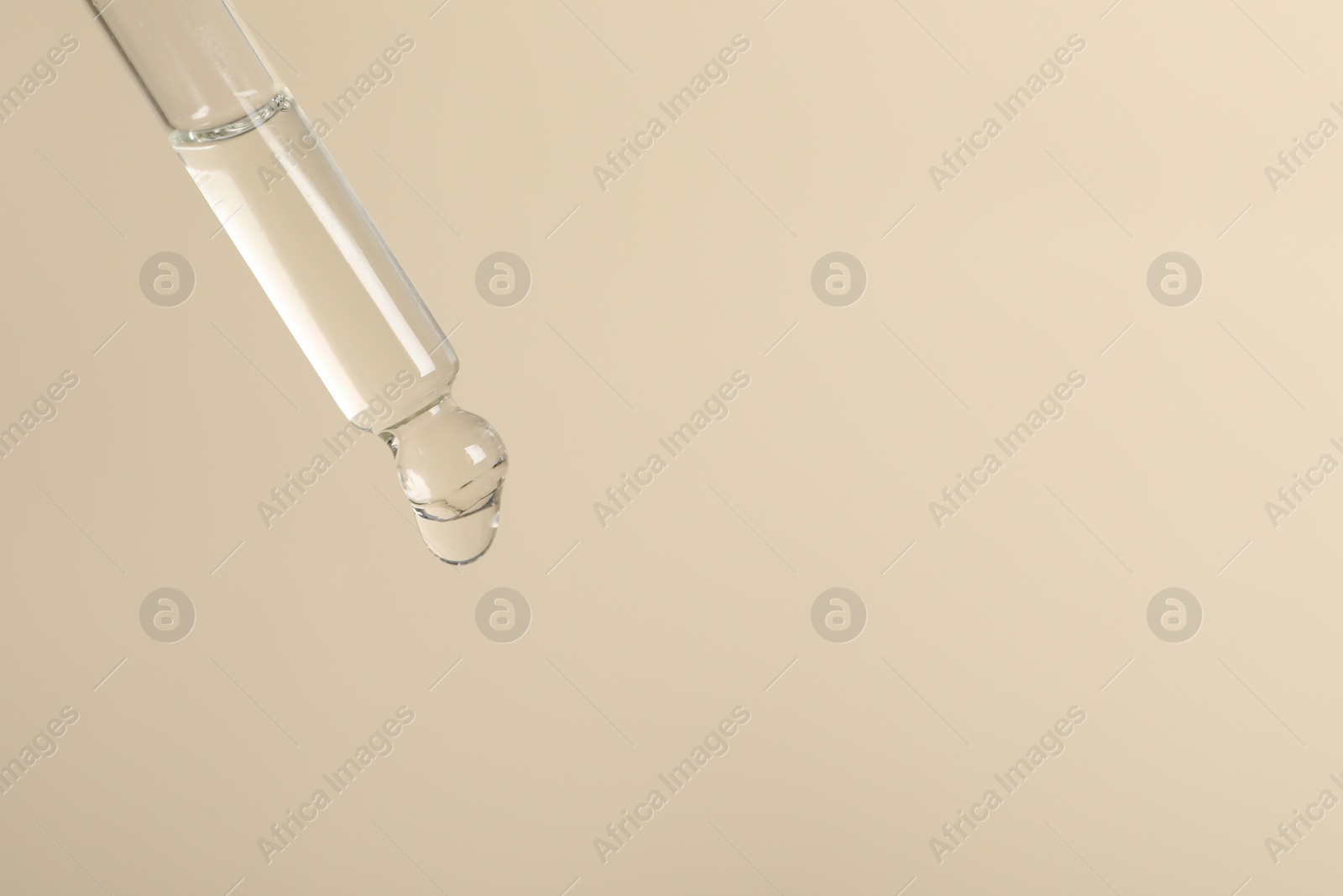 Photo of Dripping cosmetic serum from pipette on beige background, space for text