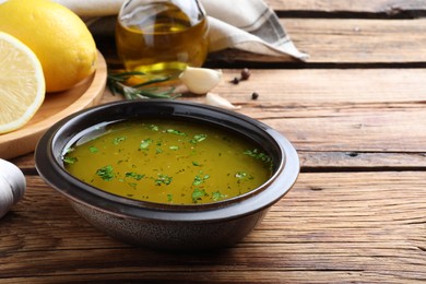 Photo of Bowl with lemon sauce and ingredients on wooden table, space for text. Delicious salad dressing