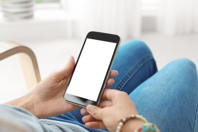 Photo of Woman holding smartphone with blank screen on blurred background. Mockup for design
