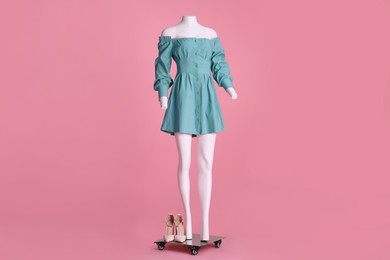 Photo of Female mannequin with shoes and necklace dressed in stylish light blue dress on pink background