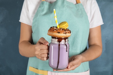 Photo of Woman with mason jar of delicious milk shake on color background, closeup