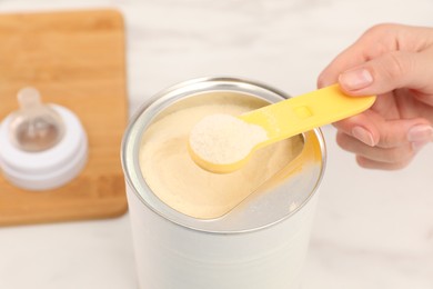 Photo of Woman with powdered infant formula at table, closeup. Preparing baby milk