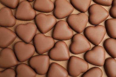 Photo of Tasty heart shaped chocolate candies on brown background, flat lay. Valentine's day celebration