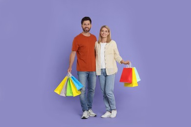 Photo of Family shopping. Happy couple with many colorful bags on violet background