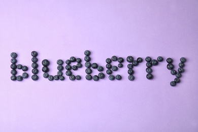Photo of Word BLUEBERRY on violet background, top view