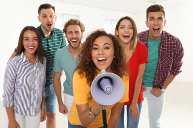 Photo of Group of happy young people with megaphone indoors