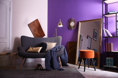 Photo of Large mirror and comfortable sofa in living room. Interior design
