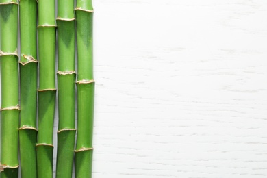 Green bamboo stems and space for text on wooden background, top view