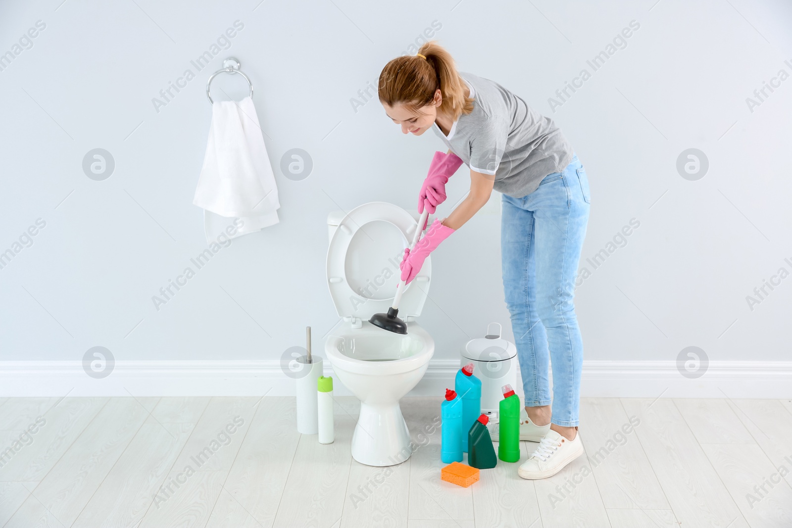 Photo of Woman cleaning toilet bowl in bathroom