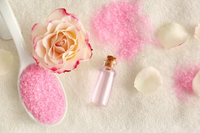 Photo of Aromatic sea salt, beautiful flower and petals on white towel, flat lay