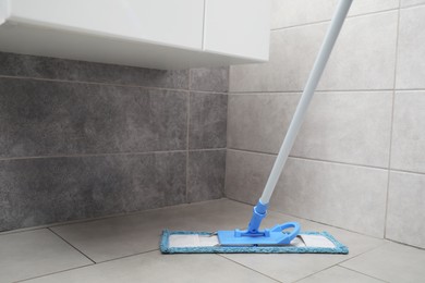 Photo of Cleaning grey tiled floor with mop indoors