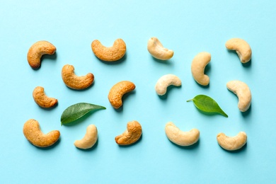 Photo of Tasty cashew nuts and leaves on color background, top view
