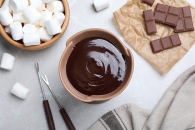Photo of Bowl with melted chocolate and marshmallows on light grey marble table, flat lay