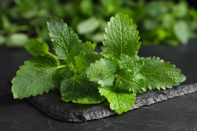 Photo of Fresh green lemon balm leaves on black table, closeup