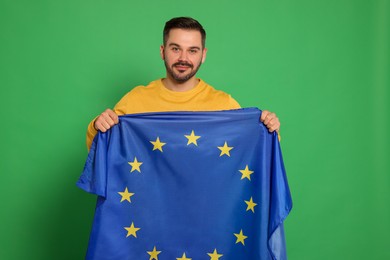 Photo of Man with flag of European Union on green background