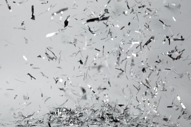 Photo of Shiny silver confetti falling down on light grey background