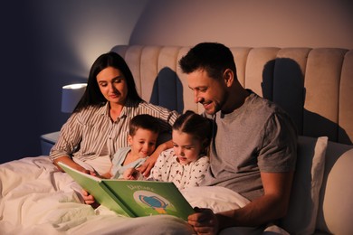 Photo of Family reading book together in bed at home