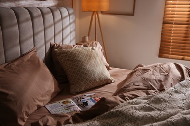 Bed with stylish linen and soft pillows in room