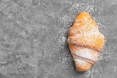 Photo of Tasty croissant with sugar powder on gray background, top view