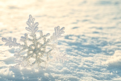 Photo of Beautiful decorative snowflake in white snow, outdoors. Space for text