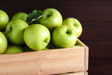Photo of Juicy green apples in crate on wooden background, closeup