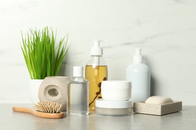 Photo of Brush and personal care products on gray table near white marble wall