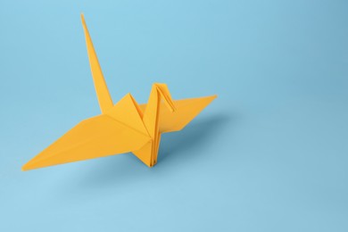 Photo of Origami art. Handmade paper crane on light blue background, space for text