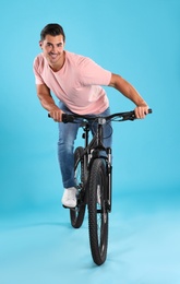 Photo of Handsome young man with modern bicycle on light blue background