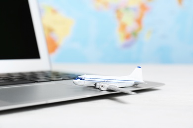 Photo of Composition with toy plane and laptop on table against map. Travel agency