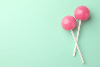 Photo of Tasty lollipops on turquoise background, flat lay. Space for text