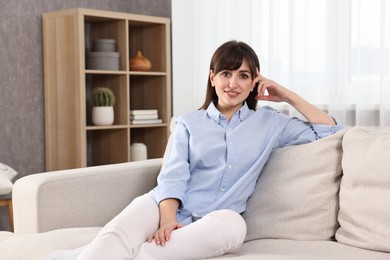 Photo of Beautiful young housewife on sofa at home