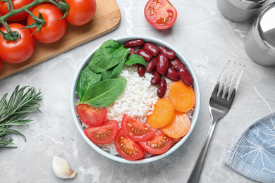 Photo of Tasty rice with beans served on light grey marble table, flat lay