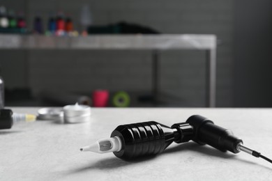 Photo of Modern professional tattoo machine on white table in salon
