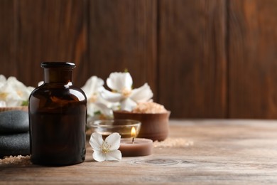 Photo of Beautiful composition with jasmine essential oil and fresh flowers on wooden table. Space for text