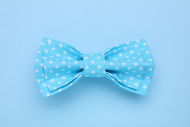 Photo of Stylish light blue bow tie with polka dot pattern on color background, top view