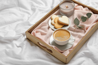 Photo of Wooden tray with coffee and cookies on bed. Romantic breakfast