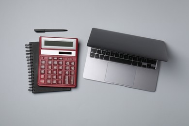 Photo of Calculator, laptop, notebook and pen on light grey background, flat lay