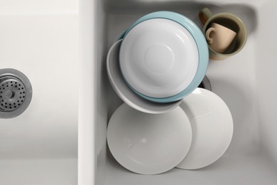 Photo of Clean tableware in white sink, top view