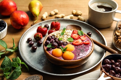Photo of Bowl of tasty acai smoothie and ingredients on wooden table