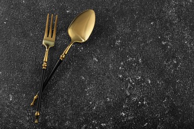 Photo of Shiny fork and spoon on black table, flat lay. Space for text