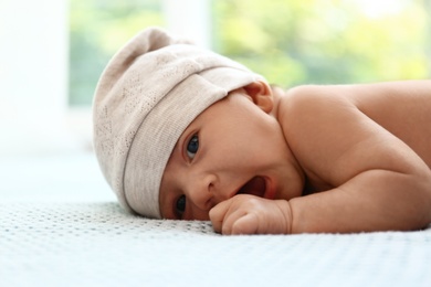 Photo of Cute little baby in hat lying on light blue plaid indoors
