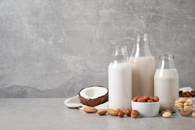 Photo of Different nut milks on light grey table. Space for text