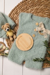 Photo of Children's clothes, toys and green plant on white wooden table, top view