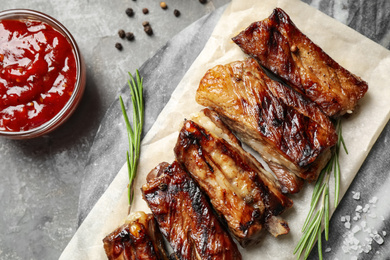Photo of Delicious grilled ribs served on grey table, flat lay