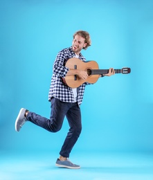 Photo of Young man playing acoustic guitar on color background