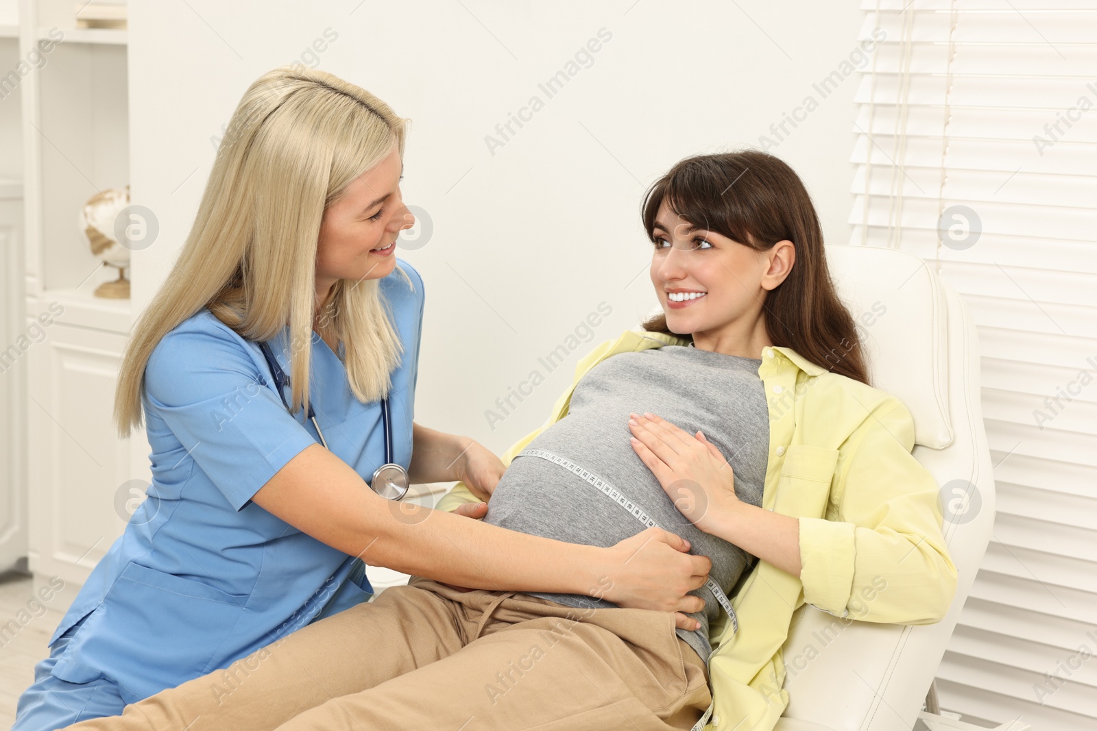 Photo of Pregnancy checkup. Doctor measuring patient's tummy in clinic