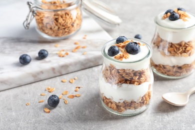 Photo of Jars with yogurt, berries and granola on  table
